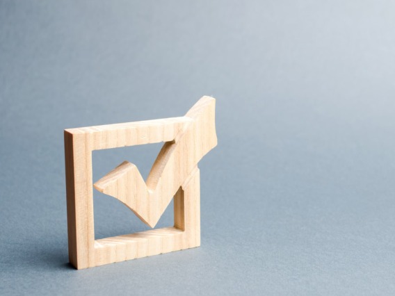 A wooden checkmark sits on a dove blue background.