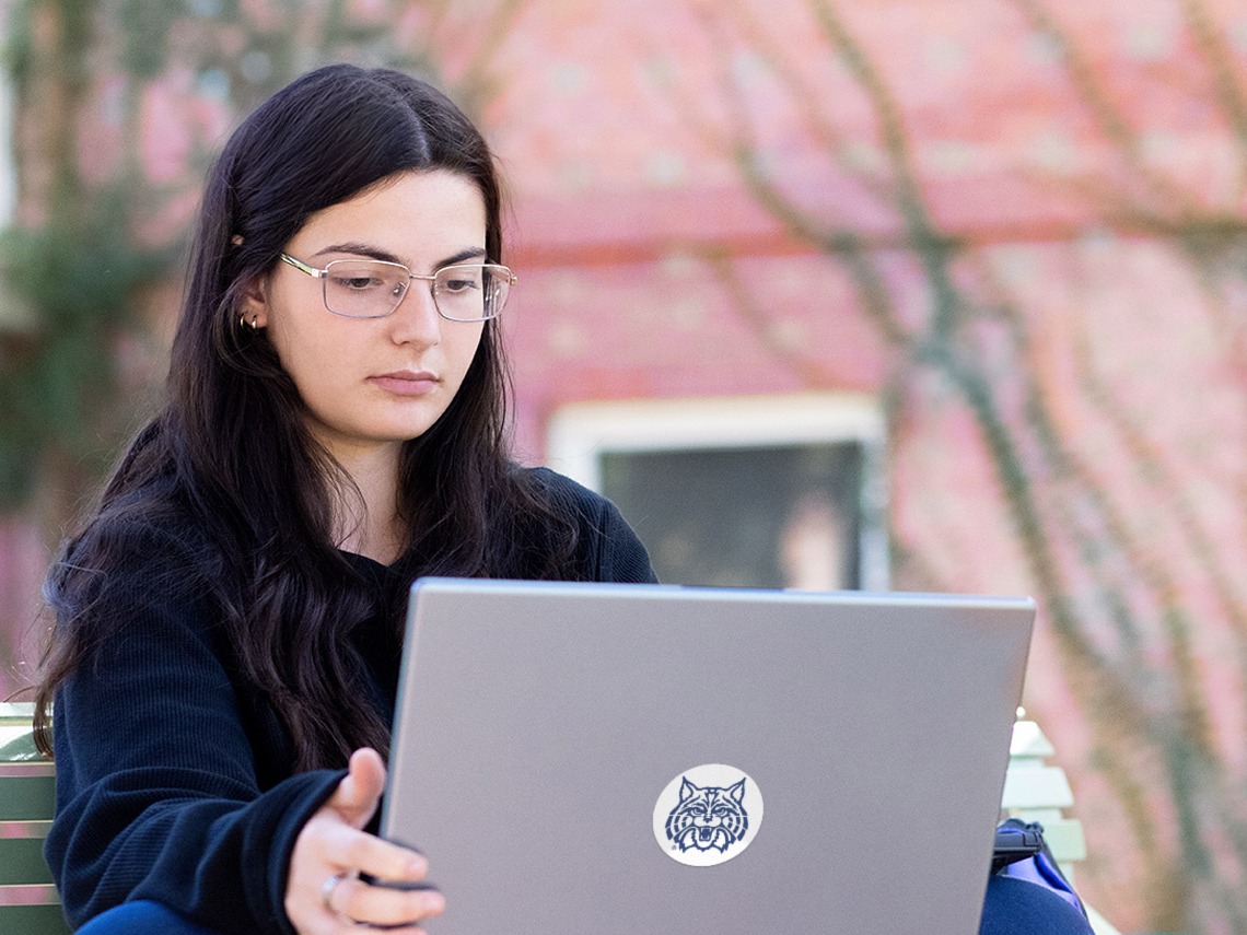 A young female student working on her laptop during an online class.